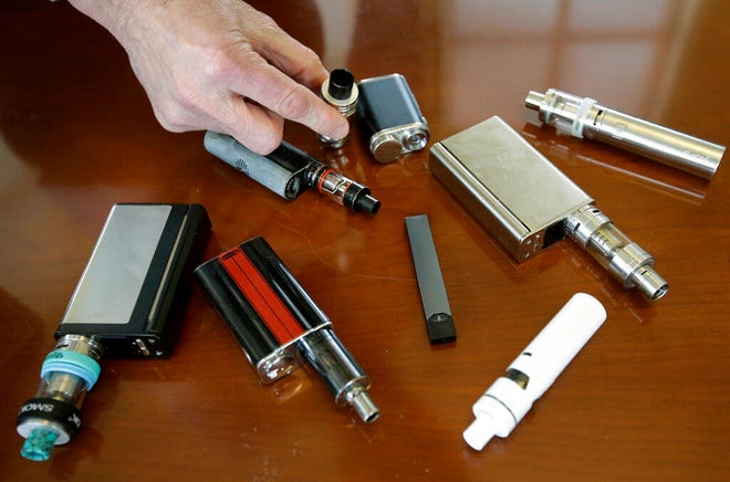 In this Tuesday, April 10, 2018 photo, Marshfield High School Principal Robert Keuther displays vaping devices that were confiscated from students in such places as restrooms or hallways at the school in Marshfield, Mass. Illinois health officials are reporting what could be United States' first death tied to vaping. In a Friday, Aug. 23, 2019, news release, the Illinois Department of Public Health says a person who recently vaped died after being hospitalized with "severe respiratory illness." The agency didn't give any other information about the patient, including a name or where the person lived. (AP Photo/Steven Senne, File)