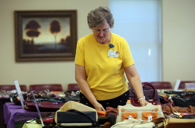 Volunteer Ruby McKinney arranges bags for sale at the Purses for a Purpose event at the administrative building for Cleveland County Hospice in Shelby. [Brittany Randolph/The Star]