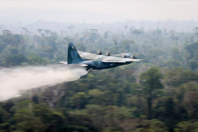In this photo released by Brazil Ministry of Defense, a C-130 Hercules aircraft dumps water to fight fires burning in the Amazon rainforest, in Brazil, Saturday, Aug, 24, 2019. Backed by military aircraft, Brazilian troops on Saturday were deploying in the Amazon to fight fires that have swept the region and prompted anti-government protests as well as an international outcry.