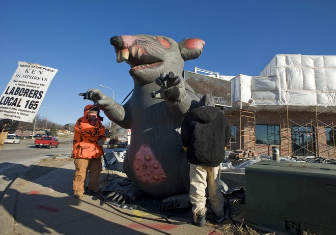 Labor International Local 165 member David Turney grabs a tether to keep the wind from pulling a giant inflatable rat positioned at Sheridan Road and Glen Avenue in Peoria during a 2011 picket. [DAVID ZALAZNIK/JOURNAL STAR FILE]