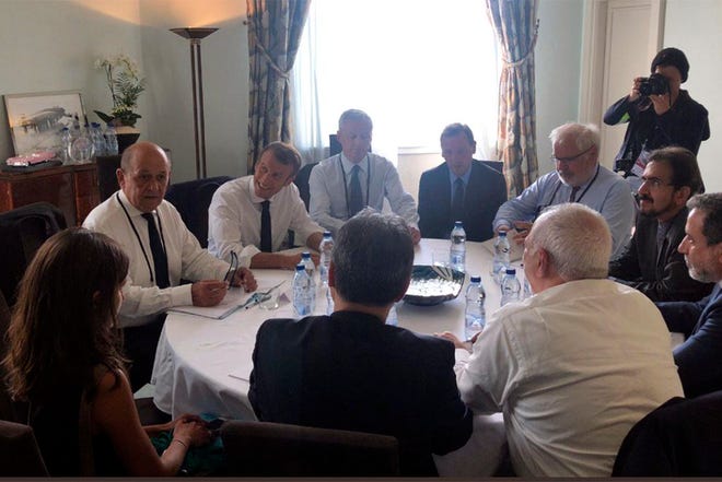 In this photo taken from the Twitter account of Iranian Foreign Minister Mohammad Javad Zarif, shows French President Emmanuel Macron, third left, French Foreign Minister Jean-Yves le Drian, second left, meeting Iranian Foreign Minister Mohammad Javad Zarif, bottom right in white shirt Sunday in Biarritz, southwestern France. Zarif paid an unannounced visit Sunday to the G-7 summit and headed straight to the buildings where leaders of the world's major democracies have been debating how to handle the country's nuclear ambitions.