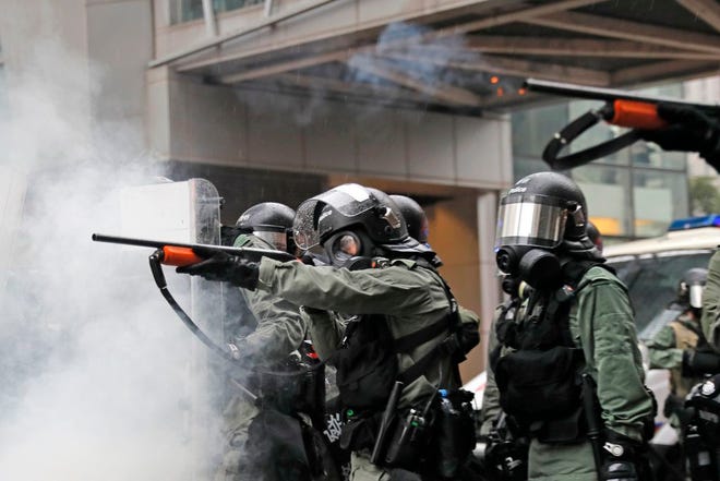 Riot policemen fire weapons during a confrontation with demonstrators during a protest in Hong Kong, on Sunday. Hong Kong police have rolled out water cannon trucks for the first time in this summer's pro-democracy protests. The two trucks moved forward with riot officers Sunday evening as they pushed protesters back along a street in the outlying Tsuen Wan district.