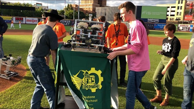 Students and coaches from Akron Public Schools high school robotics programs prepare one of their creations to throw out the first pitch Saturday at Canal Park in Akron. [Joe Thomas/Beacon Journal/Ohio.com]