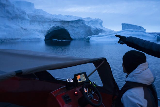 In this Aug. 16, 2019, photo, a boat navigates at night next to a large iceberg in eastern Greenland. Summer 2019 is hitting Greenland hard with record-shattering heat and extreme melt. Scientists estimate that by the end of the summer, about 440 billion tons (400 billion metric tons) of ice, maybe more, will have melted or calved off Greenland's giant ice sheet. (AP Photo/Felipe Dana)