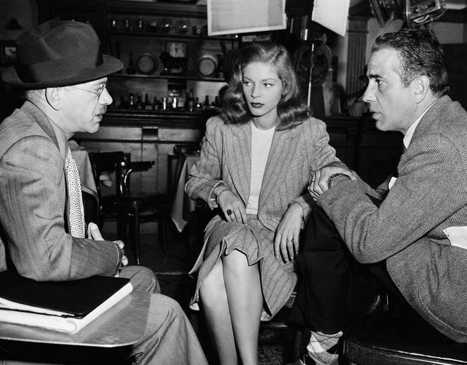 Humphrey Bogart and Lauren Bacall are shown in a huddle with director Herman Shumlin, left, between scenes on the set of the film "Confidential Agent" on July 18, 1945.