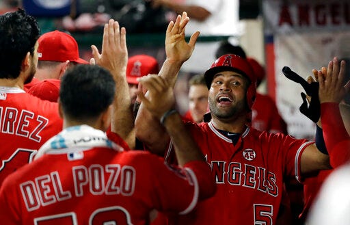 Los Angeles Angels' Albert Pujols, right, is congratulated in the dugout after scoring on a single by Brian Goodwin during the seventh inning of a baseball game against the Texas Rangers on Tuesday, Aug. 27, 2019, in Anaheim, Calif. (AP Photo/Marcio Jose Sanchez)