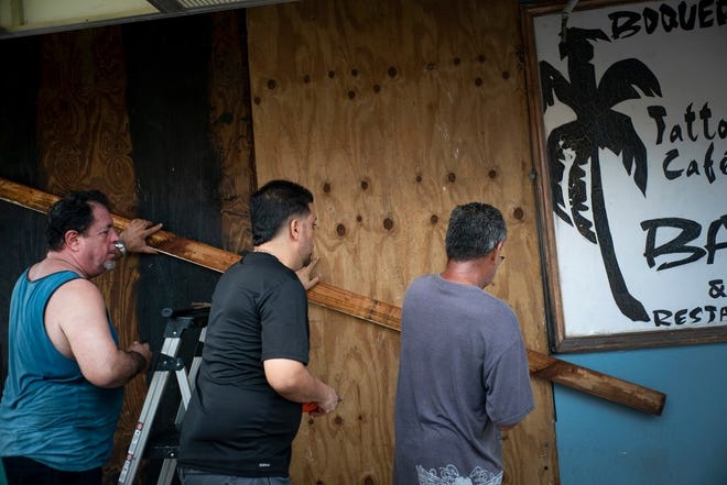 Men board up a shop's windows ahead of the arrival of Tropical Storm Dorian in Boqueron, Puerto Rico, Tuesday, Aug. 27, 2019. (AP Photo/Ramon Espinosa)