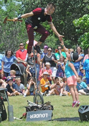 Jason D'Vaude high fives Emma Hottman, 8, while on his unicycle during the performance of Jason D'Vaude: One Man Show at the 43rd Annual Smoky Hill River Festival at Oakdale park. The Salina City Commission approved a $5 increase for advance and at-gate Smoky Hill River Festival admission to cover the increasing cost of staffing, goods and services. The festival will be using entrance wristbands instead of buttons. [JOURNAL FILE PHOTO]