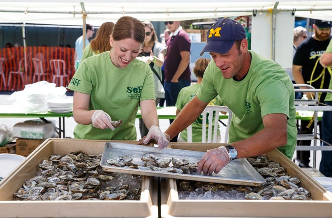 Erin Svendsen and Shane Perkins unload half-shelled oysters into ice as they serve them raw and grilled during the eighth annual Springfield Oyster and Beer Festival in 2017. [Justin L. Fowler/The State Journal-Register file photo]