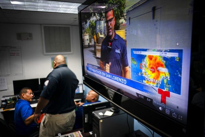 Emergency Center personnel stand next to a tv screen showing a meteorological image of the tropical storm Dorian, as they await its arrival, in Ceiba, Puerto Rico, Wednesday. Puerto Rico is facing its first major test of emergency preparedness since the 2017 devastation of Hurricane Maria as Tropical Storm Dorian nears the U.S. territory at near-hurricane force. (AP Photo/Ramon Espinosa)