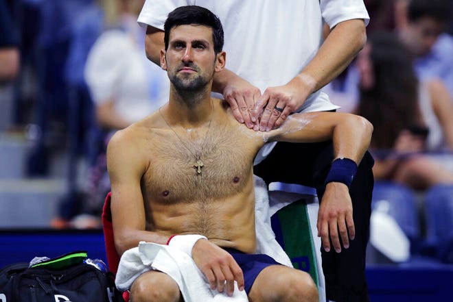 Novak Djokovic, of Serbia, receives treatment from a trainer during his match against Juan Ignacio Londero, of Argentina, during the second round of the U.S. Open tennis tournament in New York, Wednesday, Aug. 28, 2019. (AP Photo/Charles Krupa)