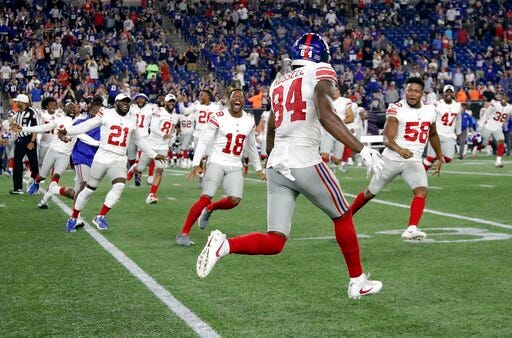 Teammates rush to congratulate New York Giants wide receiver Alonzo Russell (84) after he caught a touchdown pass to win an NFL preseason football game against the New England Patriots, Thursday, Aug. 29, 2019, in Foxborough, Mass. (AP Photo/Elise Amendola)