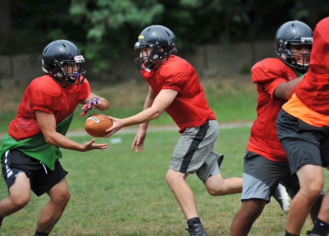 North Quincy quarterback Andrew Gott, center, hands off during football practice on Friday, Aug. 23, 2019. Tom Gorman/For The Patriot Ledger