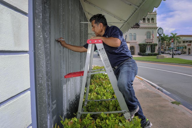 Church Mouse employee Jose Cartagena labels hurricane shutters that he began installing on the store's windows early Thursday, August 29, 2019. [Damon Higgins/palmbeachdailynews.com]