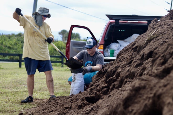 Vilano Beach resident Ryan Gaskin (right) and his dad Kevin Gaskin, a St. Augustine resident, fill up bags with dirt at North Beach Park. [TRAVIS GIBSON/THE RECORD]