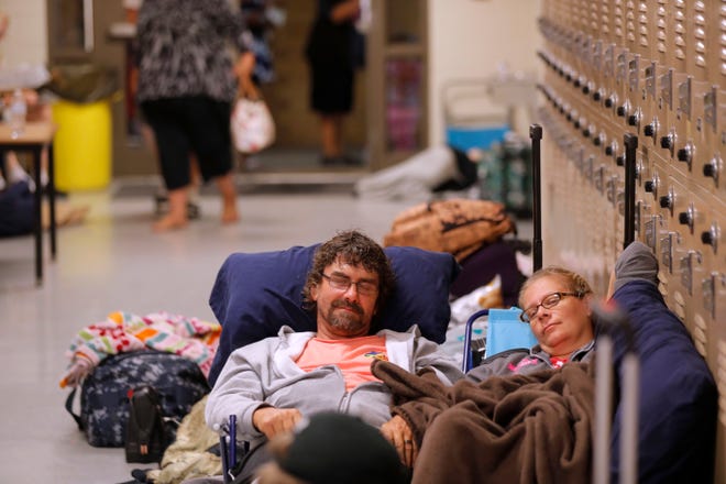 Jeff Ready and his wife Julie Ready rest in a a hallway at an evacuation shelter in advance of Hurricane Michael in Panama City Beach. [AP Photo/Gerald Herbert]