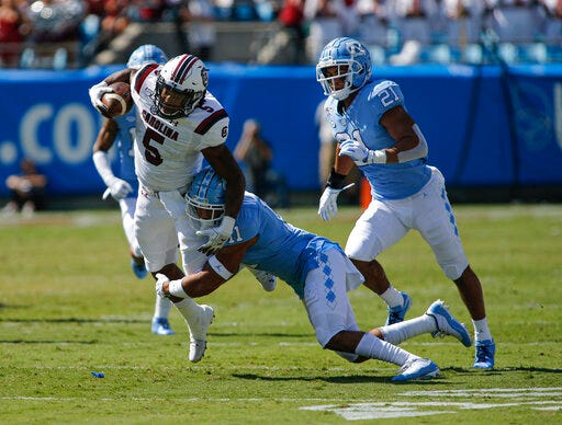 South Carolina running back Rico Dowdle, left, tries to break the tackle of North Carolina defensive back Myles Wolfolk and linebacker Chazz Surratt (21) in the first half of an NCAA college football game in Charlotte, N.C., Saturday, Aug. 31, 2019. (AP Photo/Nell Redmond)