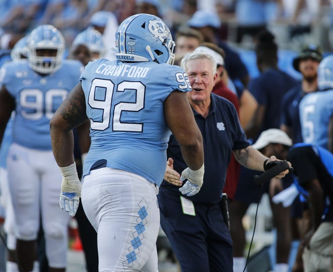 North Carolina head coach Mack Brown, right, greets defensive lineman Aaron Crawford after Crawford sacked South Carolina quarterback Jake Bentley in the second half of Saturday's game. [AP Photo/Nell Redmond]