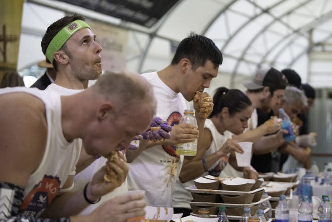 Darron Breeden, center, downs one of the 28.25 sloppers to take the title at the World Slopper Eating Championships during the Colorado State Fair in Pueblo on Saturday. [CHIEFTAIN PHOTO/ZACHARY ALLEN]
