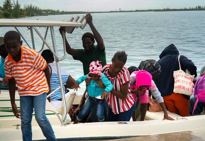 A woman carries a girl in her arms after being evacuated from a nearby Cay due to the danger of floods after arrive on a ship at the port before the arrival of Hurricane Dorian in Sweeting's Cay, Grand Bahama, Bahamas, Saturday Aug. 31, 2019.  Dorian bore down on the Bahamas as a fierce Category 4 storm Saturday, with new projections showing it curving upward enough to potentially spare Florida a direct hit but still threatening parts of the Southeast U.S. with powerful winds and rising ocean water that causes what can be deadly flooding. (AP Photo/Ramon Espinosa)