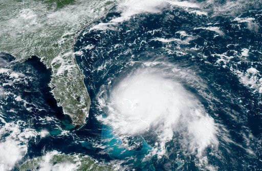 This GOES-16 satellite image taken Sunday, Sept. 1, 2019, at 17:00 UTC and provided by National Oceanic and Atmospheric Administration (NOAA), shows Hurricane Dorian, right, churning over the Atlantic Ocean. Hurricane Dorian struck the northern Bahamas on Sunday as a catastrophic Category 5 storm, its 185 mph winds ripping off roofs and tearing down power lines as hundreds hunkered in schools, churches and other shelters. (NOAA via AP)