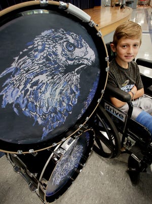 Fairless Elementary School third-grader Wesley Smith sits next to some of the marching band's bass drums. His artwork of a falcon is on the drums. (IndeOnline.com / Kevin Whitlock)