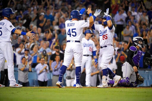 Los Angeles Dodgers' Russell Martin (55) is congratulated by Matt Beaty (45) and Cody Bellinger, left, after hitting a three-run home run, as Colorado Rockies catcher Tony Wolters kneels at the plate during the seventh inning of a baseball game Tuesday, Sept. 3, 2019, in Los Angeles. (AP Photo/Mark J. Terrill)