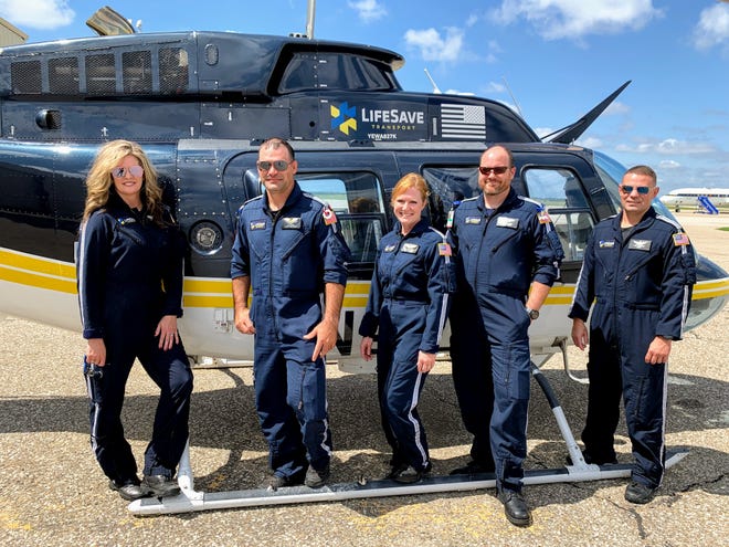 Members of LifeSave, nurse Cassie Markley, paramedic CJ Johns, clinical program manager Katie Sparks, nurse Stephen Baker and pilot Joe Priester stand in front of the helicopter near Hanger 509. [Sylvia Kvacik/Salina Journal]