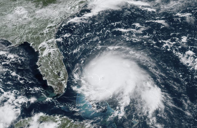 This GOES-16 satellite image taken Sunday shows Hurricane Dorian, right, churning over the Atlantic Ocean. [NOAA via AP]