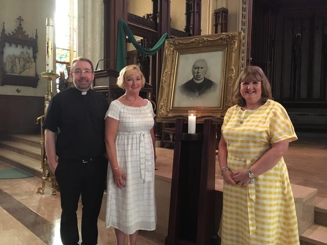 Father Tom Washburn and sisters Patricia (Murphy) Hogan and Yvonne (Murphy) Naylor of Liverpool, England, pose with an image of the ladies' great-great-great-great uncle Father Edward Murphy, founder of St. Mary's Cathedral, built from 1852 to 1856. [Deborah Allard]