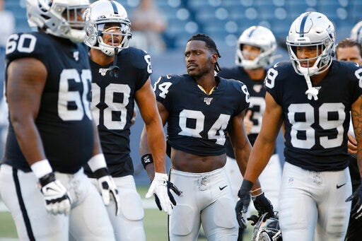 FILE - In this Aug. 22, 2019, file photo, Oakland Raiders' Antonio Brown (84) and teammates gather before an NFL preseason football game against the Green Bay Packers in Winnipeg, Manitoba. Star receiver Antonio Brown is not with the Oakland Raiders four days before the season opener amid reports he could be suspended over a confrontation with general manager Mike Mayock. Mayock issued a brief statement at the beginning of practice Thursday, Sept. 5, 2019, saying that Brown wasn't at the Raiders facility and won't be practicing a day after Brown posted a letter from the GM on social media detailing nearly $54,000 in fines (John Woods/The Canadian Press via AP, File)