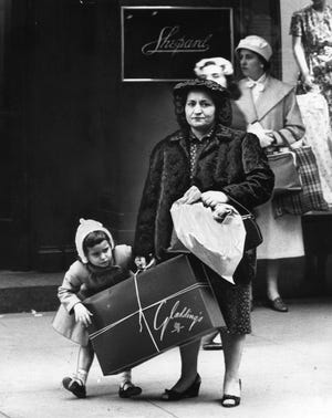 A shopper totes purchases from Gladding's and more in front of the Shepard department store in 1958. [The Providence Journal, file / John P. Callahan]