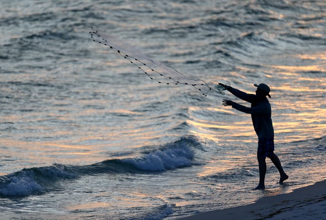 A fisherman casts a net into the water at sunset on June 17 at Panama City Beach. Saturday, Sept. 7, is license-free saltwater fishing day, when the Florida Fish and Wildlife Conservation Commission waives licenses for recreational anglers. [PATTI BLAKE/THE NEWS HERALD]
