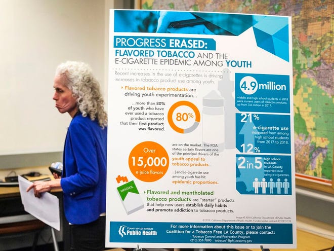 Barbara Ferrer, director of the Los Angeles County Department of Public Health, walks past a poster reading: "Progress Erased: Flavored Tobacco and the e-cigarette epidemic among youth," as the county announce the first known death associated with e-cigarette vaping at a news conference in Los Angeles on Friday. The department says in an advisory that 12 cases of pulmonary injury associated with use of e-cigarettes have been reported in Los Angeles County, and urges the public to take precautions. Earlier this month, U.S. health officials said they had identified 450 possible illnesses.