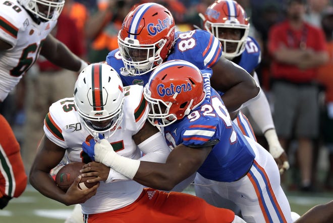 Miami quarterback Jarren Williams, left, is sacked by defensive linemen Adam Shuler, center, and Jabari Zuniga, right, during the first half of their game on Aug. 24 in Orlando. Williams was sacked 10 times during the game, a Florida victory. [FILE/THE ASSOCIATED PRESS]