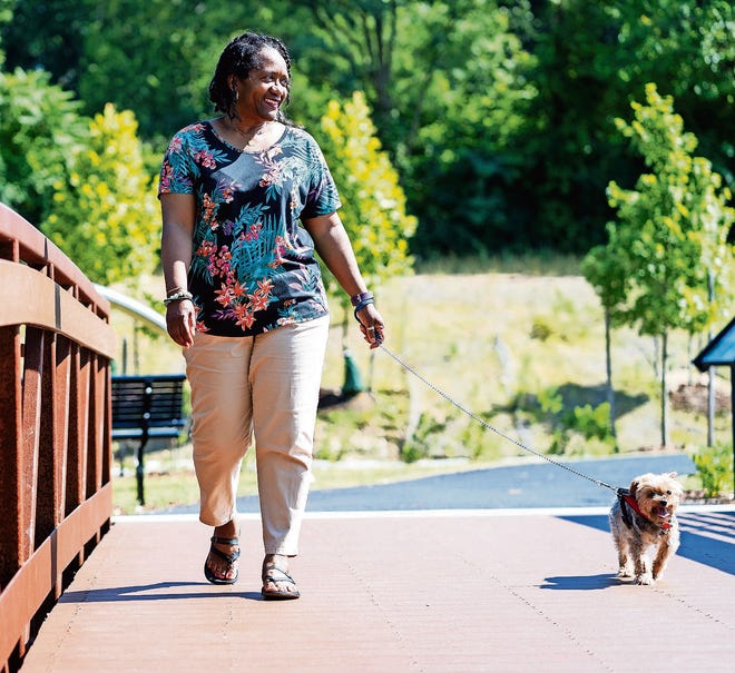 Sonia Anderson and Bronx, her Yorkshire terrier, walk on the trails near her apartment complex in Alexandria, Va. [SCOTT SUCHMAN FOR KHN]