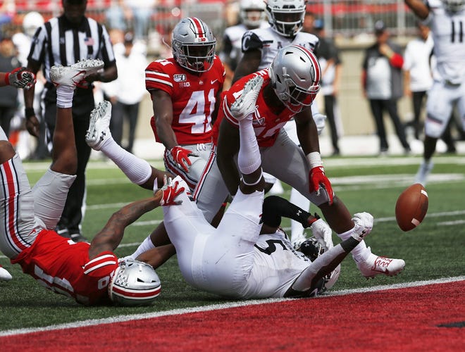 As Ohio State cornerback Amir Riep, left, pulls Cincinnati running back Tavion Thomas to the ground, linebacker Dallas Gant slaps the ball free late in the game. Cornerback Marcus Williamson recovered in the end zone to preserve the Ohio State shutout. [Fred Squillante/Dispatch]