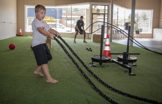 Wesley Kurtz, 6, of Ramseur, works out with dad, Josh Kurtz, in back, as they excercise with heavy rope at The Fit District in Ramseur. 

[PAUL CHURCH/THE COURIER-TRIBUNE]