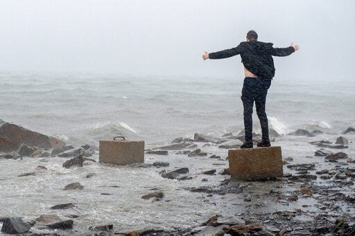 An unidentified man raises his arms in the winds from Hurricane Dorian along the Halifax harbor in Dartmouth, Nova Scotia, Canada, on Saturday, Sept. 7, 2019. (Andrew Vaughan/The Canadian Press via AP)