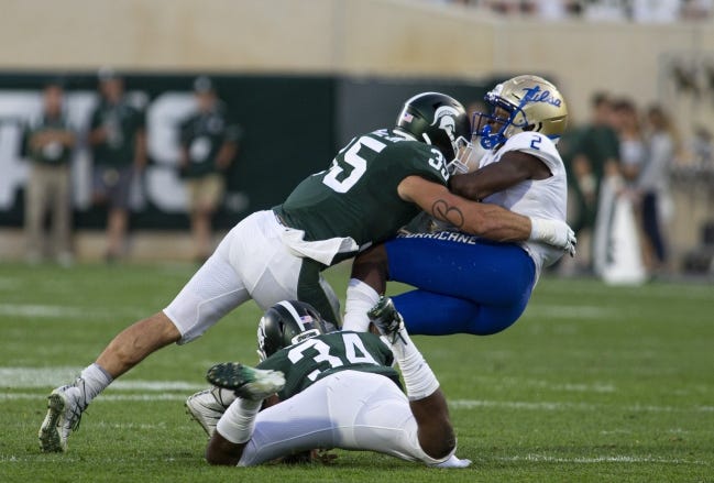 Michigan State linebackers Joe Bachie (35) and Antjuan Simmons (34) tackle Tulsa receiver Keylon Stokes (2) during the Spartans' 28-7 win Aug. 30. [AP Photo/Tony Ding]