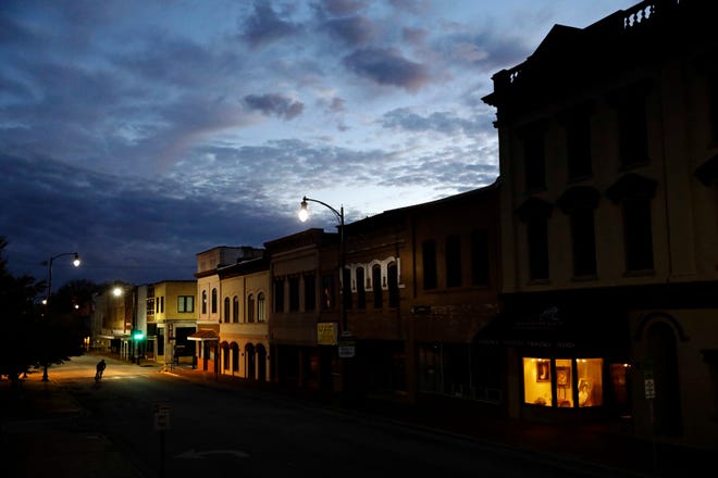 The storefront window of a portrait studio is lit up along a downtown street at dusk in Lumberton, N.C. Despite a decade-plus of economic growth, Americans have slowed the pace at which they’re forming new companies. [DAVID GOLDMAN/ASSOCIATED PRESS]