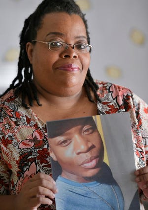Monique Veney shows a photo of her son, Darren Laval Carter, 30, who was the city's 93rd homicide victim of the year July 24. [Will Dickey/Florida Times-Union]