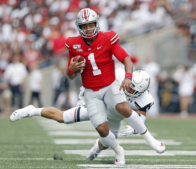 Ohio State quarterback Justin Fields shakes off Cincinnati linebacker Joel Dublanko during the first quarter of the Buckeyes' 42-0 win Saturday. Fields threw two touchdowns and ran for two more. [Kyle Robertson/Dispatch]