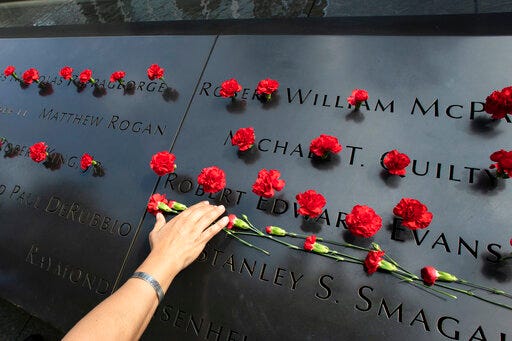 Norma Molina, of San Antonio, Texas, leaves flowers by the names of firefighters from Engine 33 at the September 11 Memorial, Monday, Sept. 9, 2019, in New York. Her boyfriend Robert Edward Evans, a member of Engine 33, was killed in the north tower of the World Trade Center on Sept. 11, 2001. (AP Photo/Mark Lennihan)