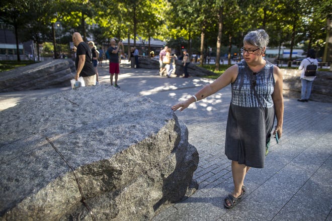A visitor touches one of the granite slabs at the 9/11 Memorial Glade at the National September 11 Memorial & Museum in New York. The granite slabs recognize an initially unseen toll of the 2001 terrorist attacks: firefighters, police and others who died or fell ill after exposure to toxins unleashed in the wreckage. [AP Photo/Mary Altaffer]