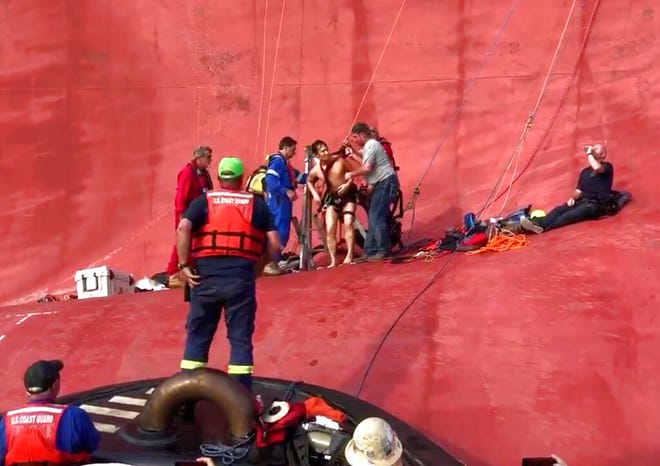 In this image taken from U.S. Coast Guard video on Monday, Sept. 9, 2019, a crew member of a capsized cargo ship is pulled from the vessel by Coast Guard rescuers off Jekyll Island, Ga. Coast Guard rescuers pulled four trapped men alive from the ship Monday, drilling into the hull's steel plates to extract the crew members more than a day after their vessel overturned while leaving a Georgia port. (U.S. Coast Guard via AP)