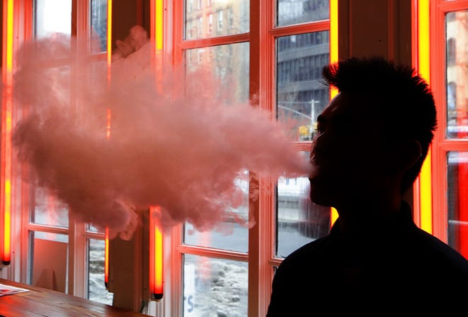In this Feb. 20, 2014, file photo, a patron exhales vapor from an e-cigarette at a store in New York. State health officials have received several potential reports of illness in Florida, though the Department of Health declined to give the precise number of reported cases. The Centers for Disease Control and Prevention said on its website that a multistate investigation has not identified any specific substance or e-cigarette product that is linked to all cases. though many patients reported using liquids that contained cannabinoid products. [Frank Franklin II/The Associated Press/File]