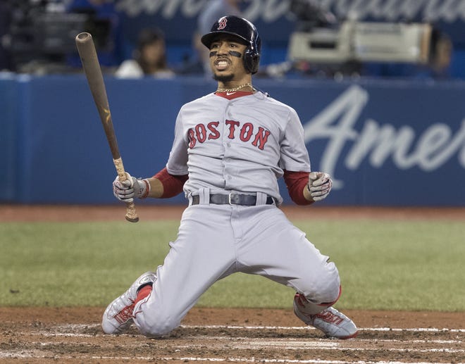 Mookie Betts drops to his knees after being backed off the plate by an inside pitch in the seventh inning of Tuesday night's Red Sox loss to the Blue Jays in Toronto. (Fred Thornhill/The Canadian Press via AP)