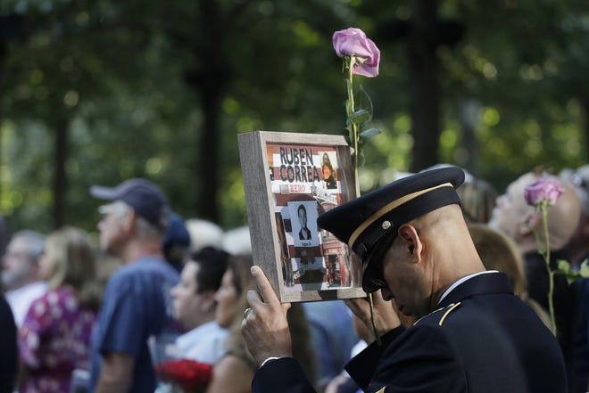 A man holds a photo of a victim during a ceremony marking the 18th anniversary of the attacks of Sept. 11, 2001, at the National September 11 Memorial Wednesday in New York. [AP Photo/Mark Lennihan]