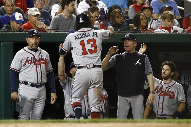 The Atlanta Braves' Ronald Acuna Jr. (13) high-fives teammates and coaches in the dugout after scoring on Nick Markakis' sacrifice fly during the fifth inning against the Nationals on Friday in Washington. [PATRICK SEMANSKY/THE ASSOCIATED PRESS]